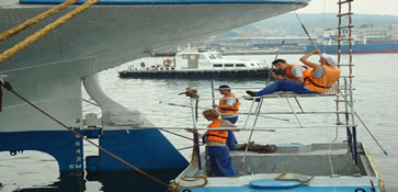 De matrozen schilderen het achterschip van de Doulos in de haven van Keelung, Taiwan. We worden de hele dag bewaakt door de politieboot op de achtergrond. Let ook op de klinknagels overal, ze zijn net zichtbaar. Schepen worden al zeker een halve eeuw gelast in plaats van geklonken.